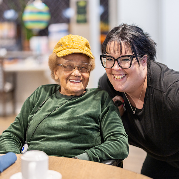A senior resident in a wheelchair smiling next to Resident Service Direct shows the bond and joy between generations.