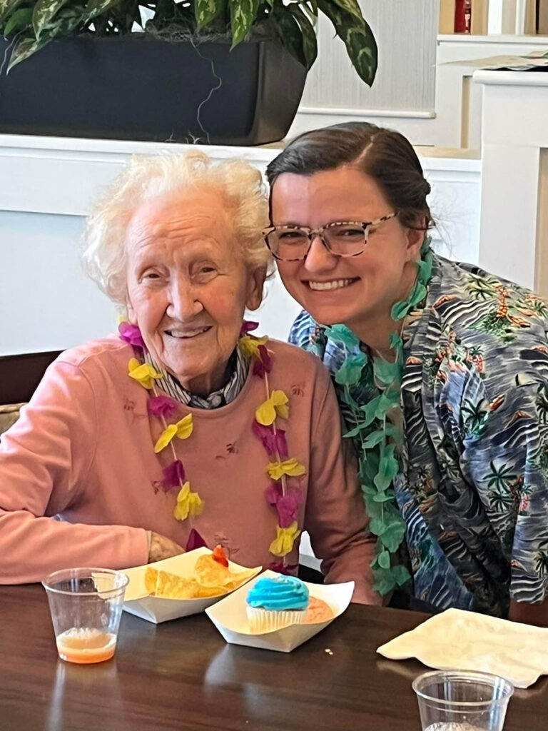 Image of two women at a table with food - one is a memory care resident and the other is an employee, enjoying brunch together.