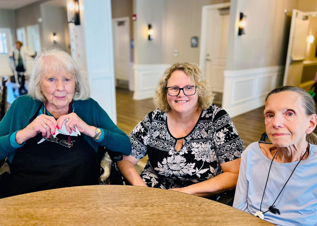 Three senior women sit together at a table at Vitalia Montrose.