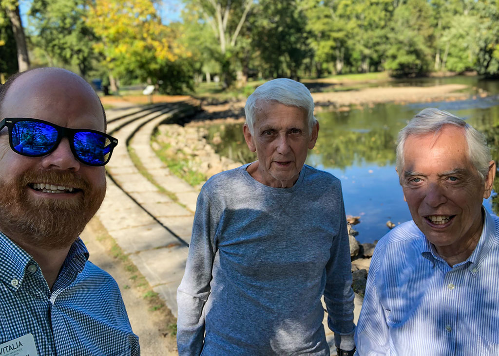 A team member and senior residents enjoy a sunny day out at a local pond.