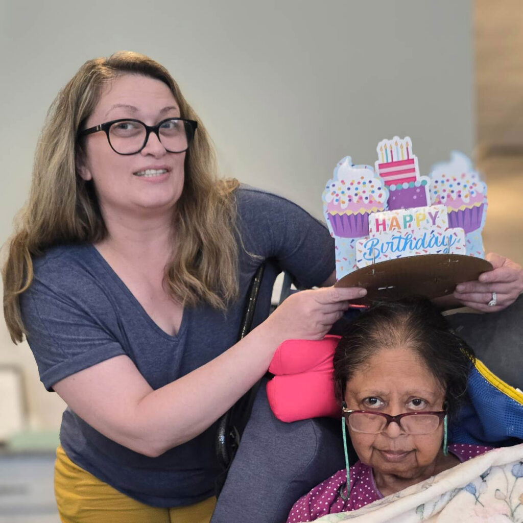A loved one places a happy birthday crown on a senior resident at Vitalia Montrose.