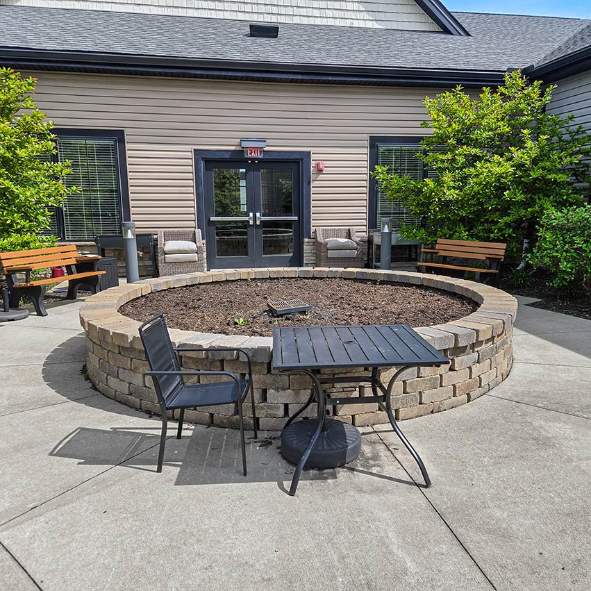 A large, circular raised flower bed flanked by trees in a seating area outside Vitalia Montrose.